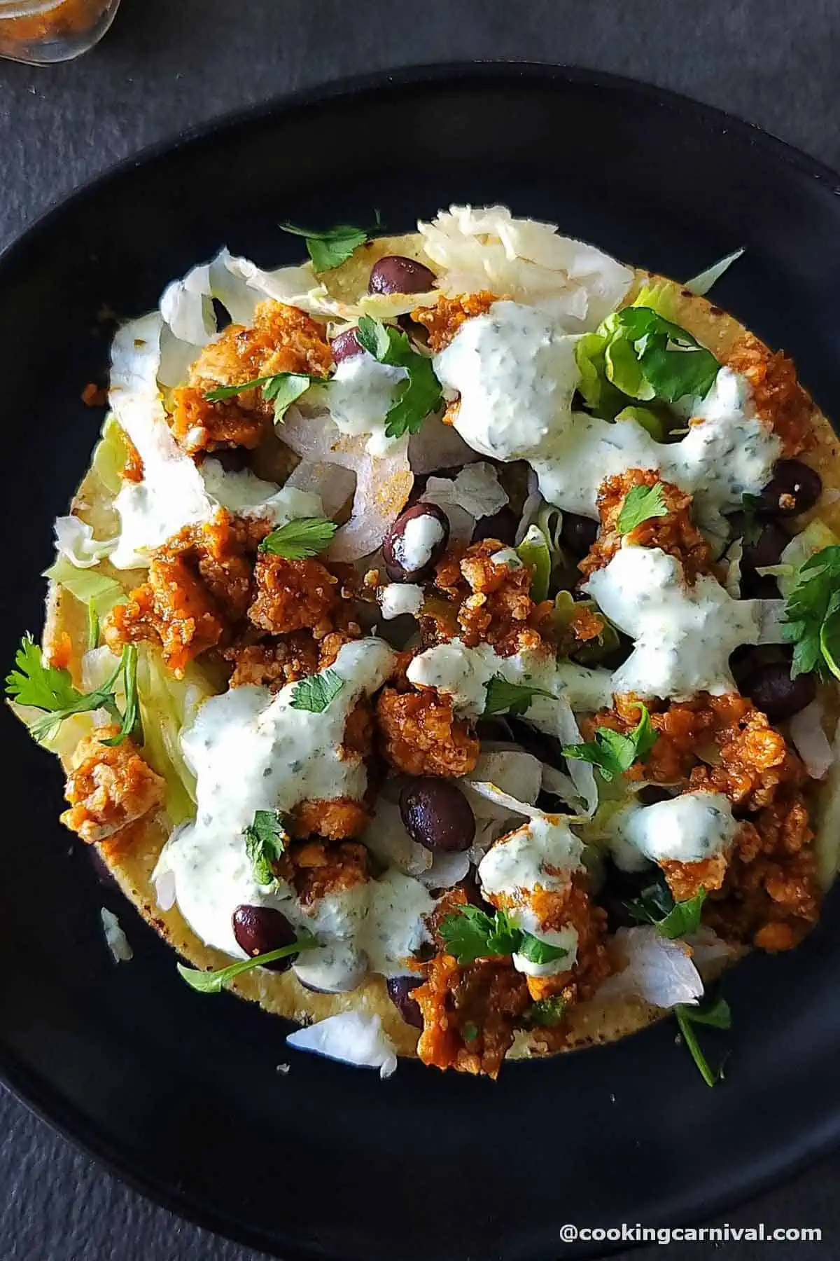 sofritas served on tostadas with lettuce, cilantro crema, and beans.