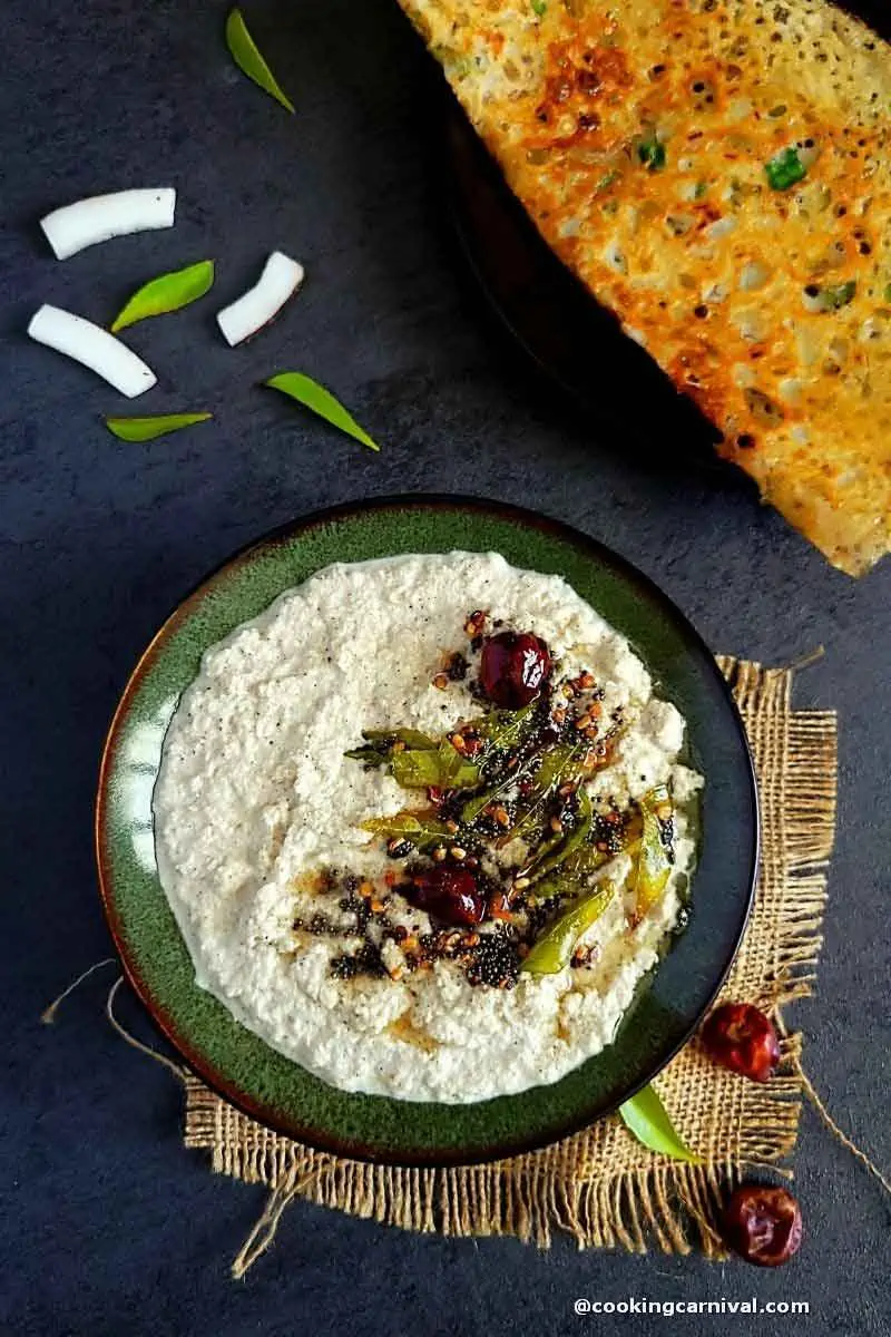 coconut chutney with tempering in a bowl, dosa on a side