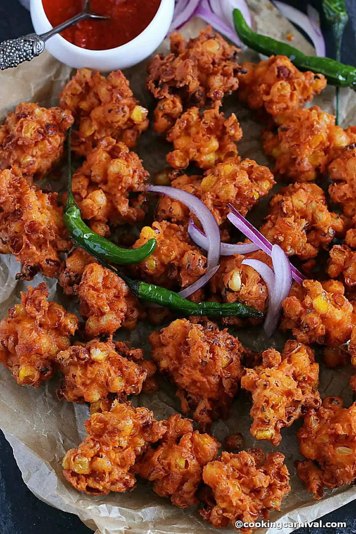 close up shot of corn fritters, onion, fried chilies and chutney.