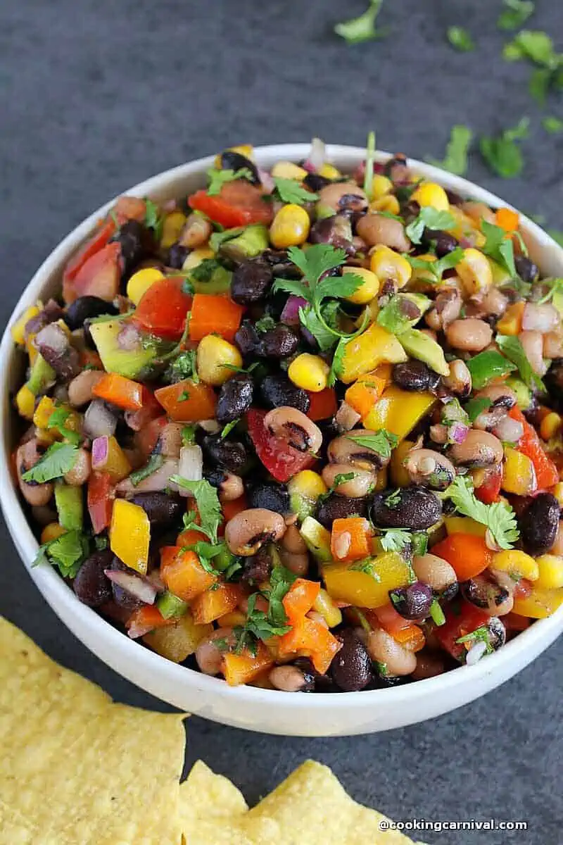 cowboy caviar made with lots of vegetables and beans with simple vinaigrette. Served in white bowl.