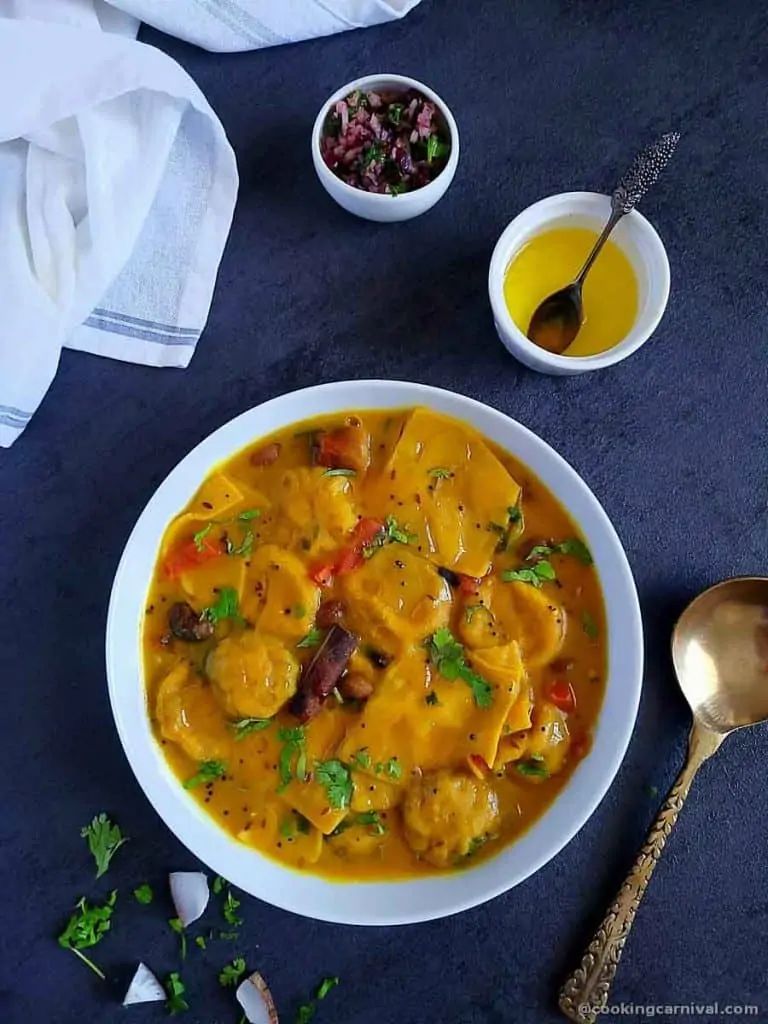 Dal dhokli in a white bowl, ghee on the side