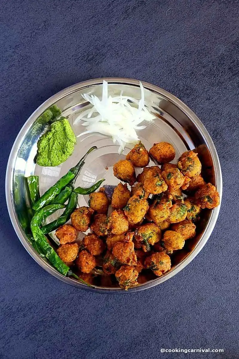 dal vada, green chilies, onion, green chutney in a steal plate.