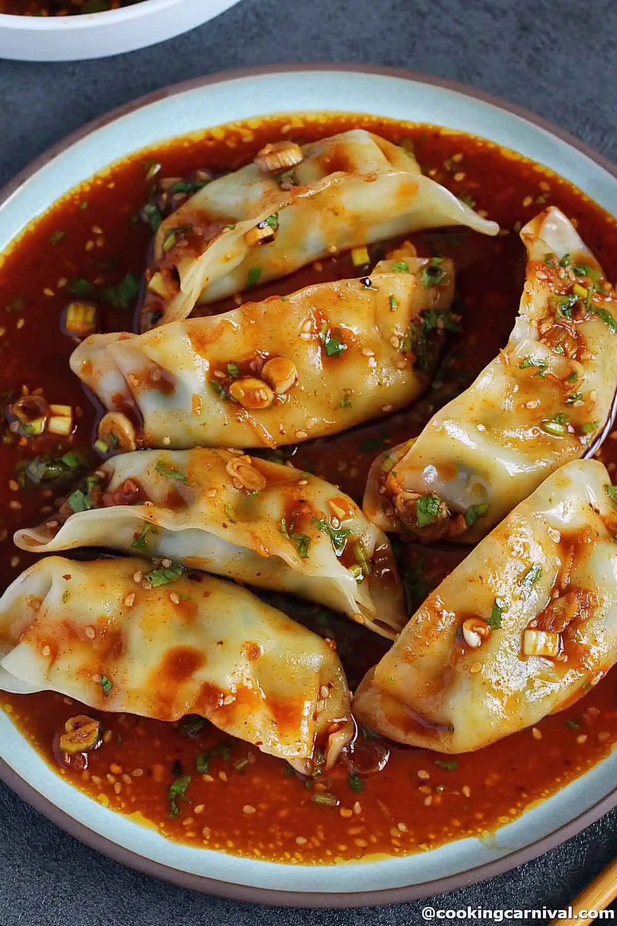 dumpling with dipping sauce in a white bowl.