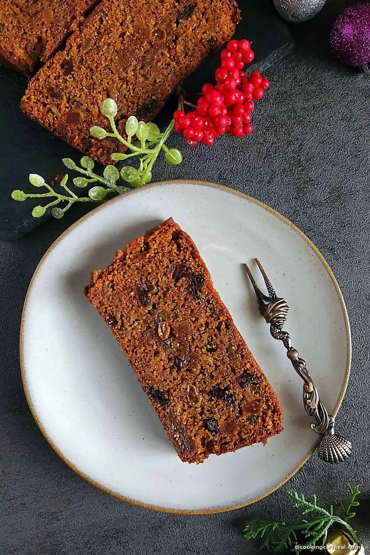 Slice of christmas fruit cake in a plate with fork.