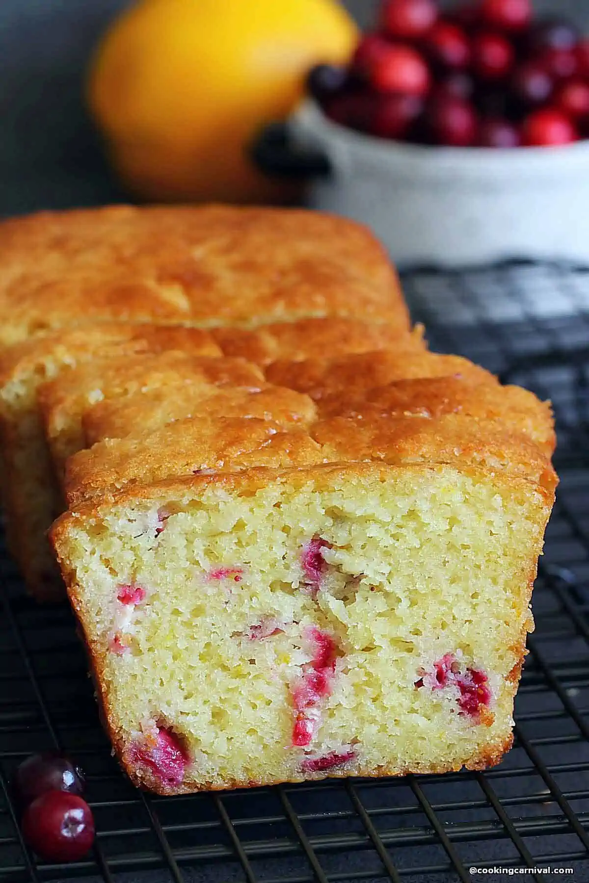 Slices of orange cranberry bread on a black board.