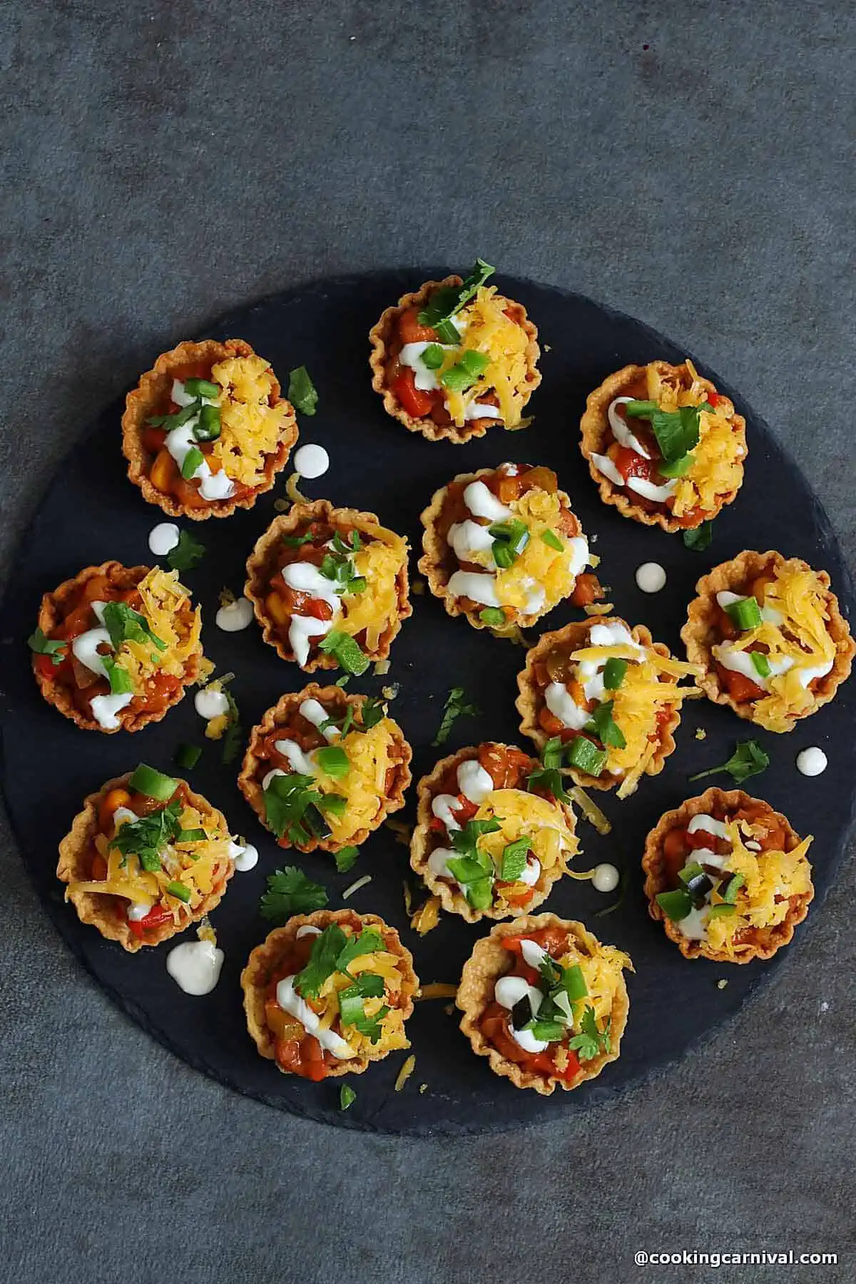 Enchilada bites on a black cheese board.