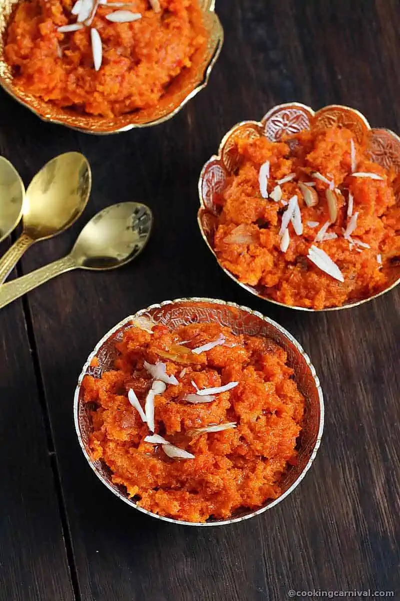 3 bowls of Gajar halwa (carrot pudding) on brown board.