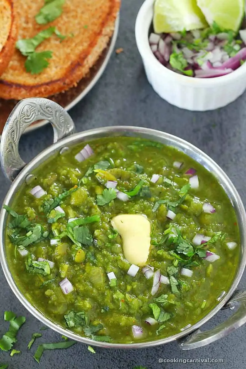 hariyali pav bhaji in a steel bowl, butter and onion on top