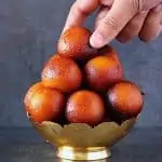 picking gulab jamun from a bowl