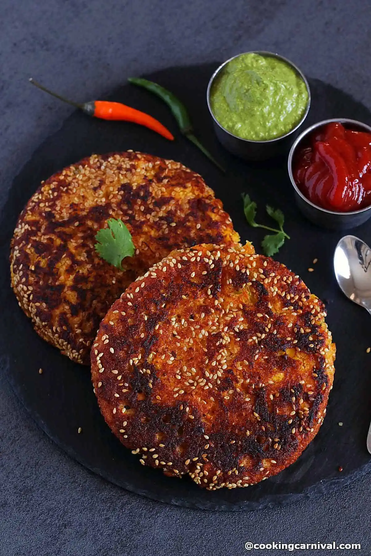 Handvo on a black cheese board, green chutney and tomato ketchup on a side.