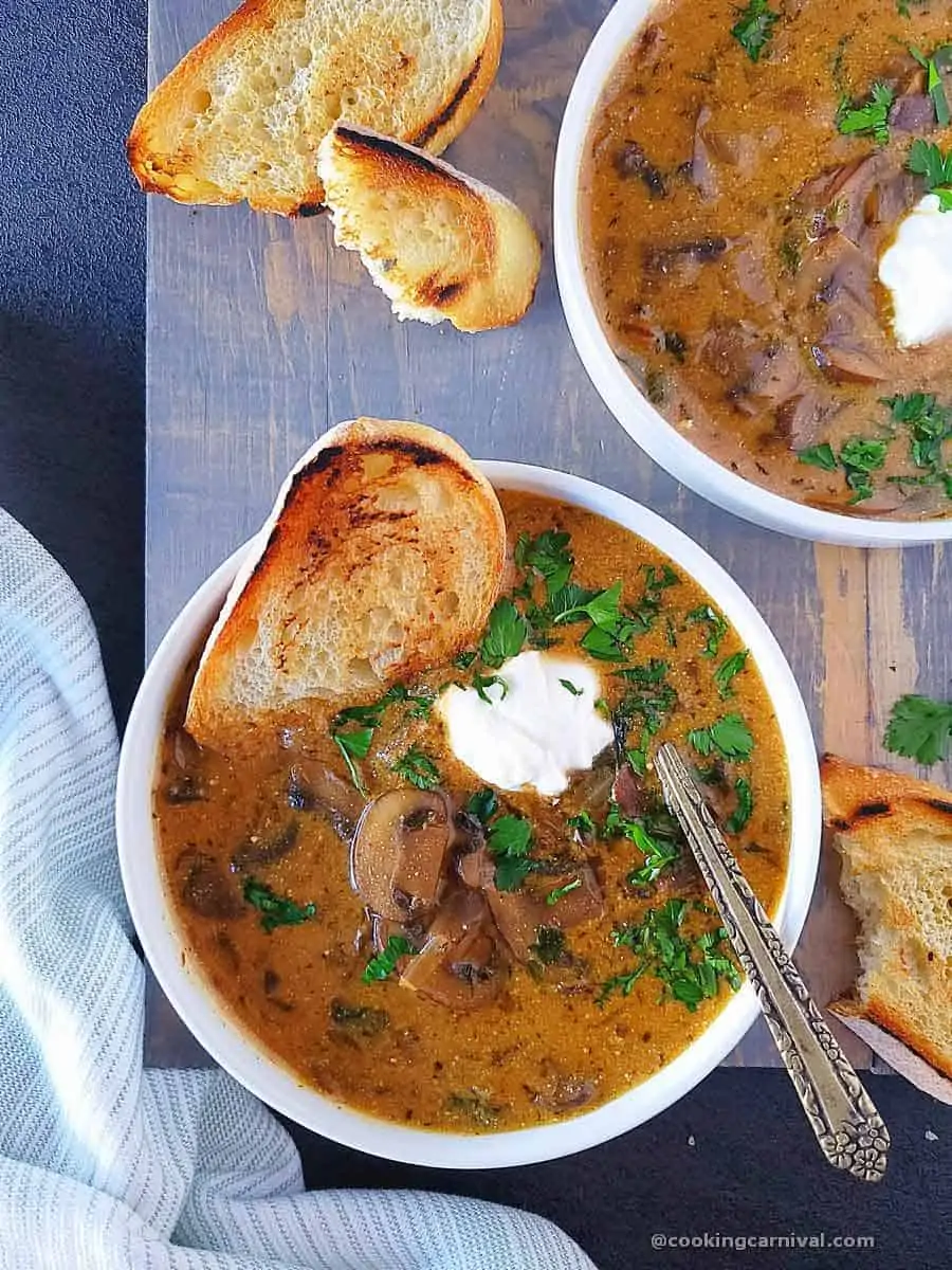 Hungarian Mushroom soup garnished with sour cream and parsley, served with crusty bread