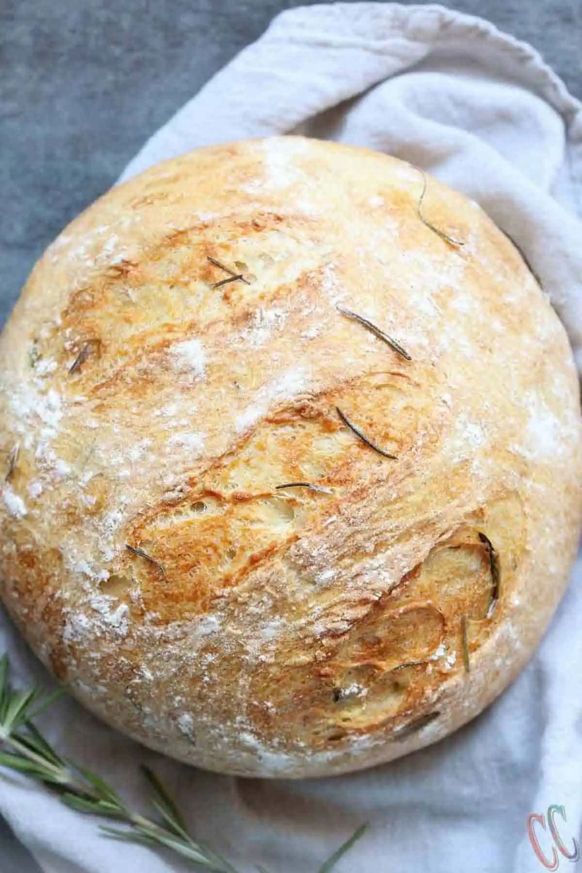 Instant pot bread flavored with rosemary and olive oil on a black tile.