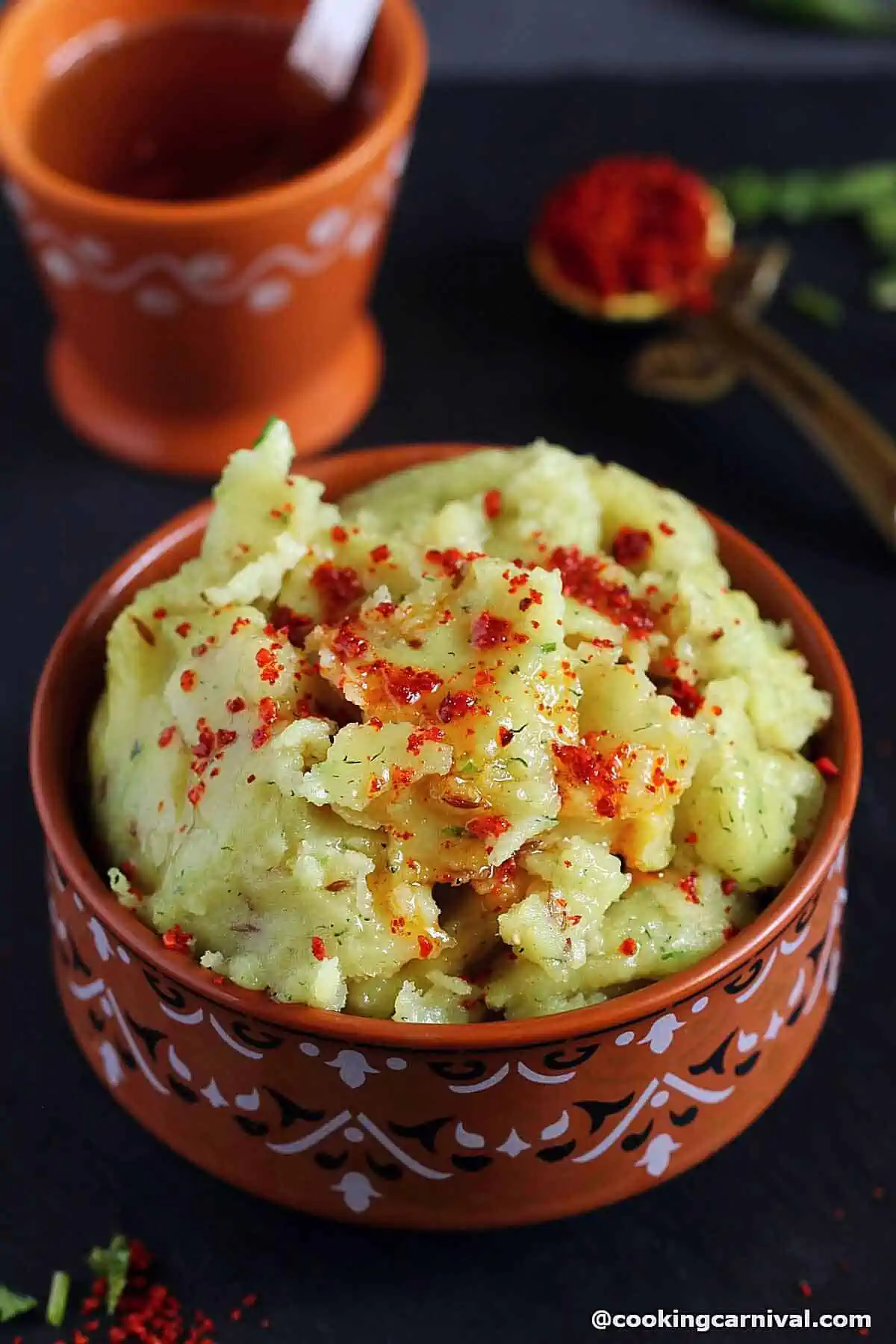 Khichu in a brown bowl, topped with peanut oil and methia masala.