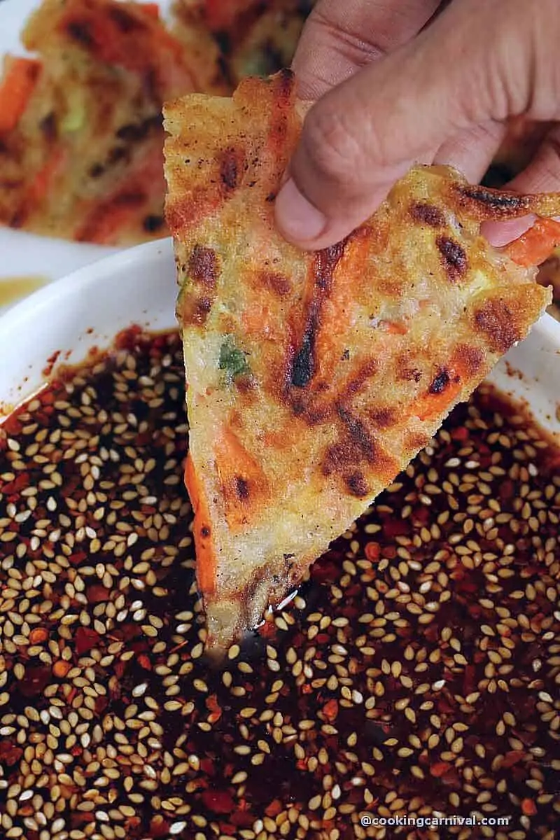 Dipping korean pancake in dipping sauce