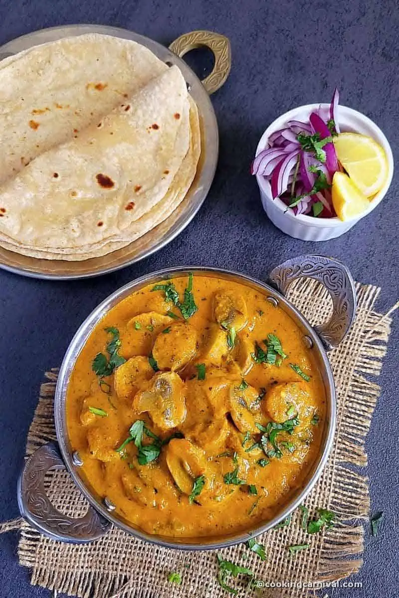 mushroom masala in a bowl, roti, onion and lemon on side.