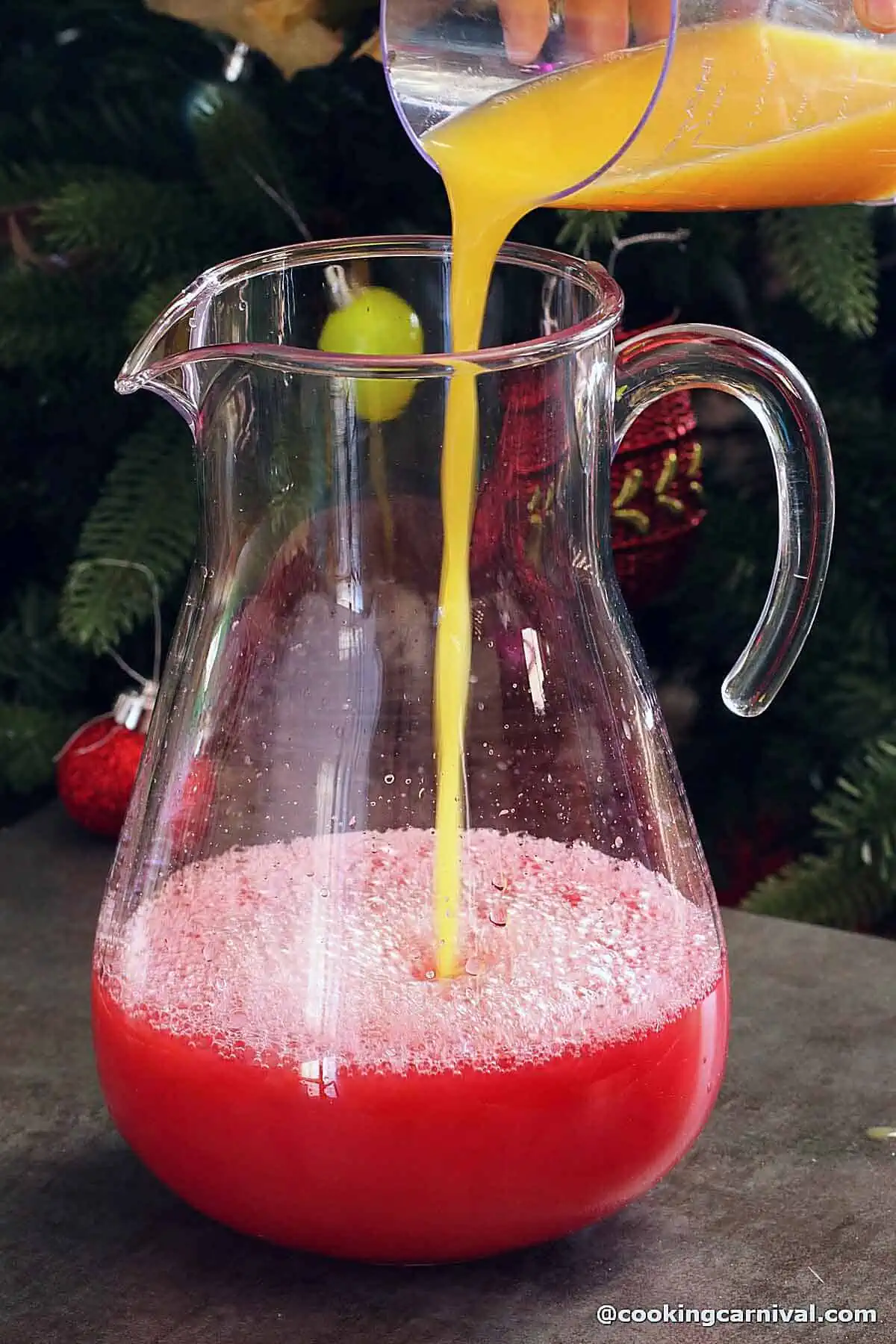 adding orange juice to a jug filled with cranberry juice.