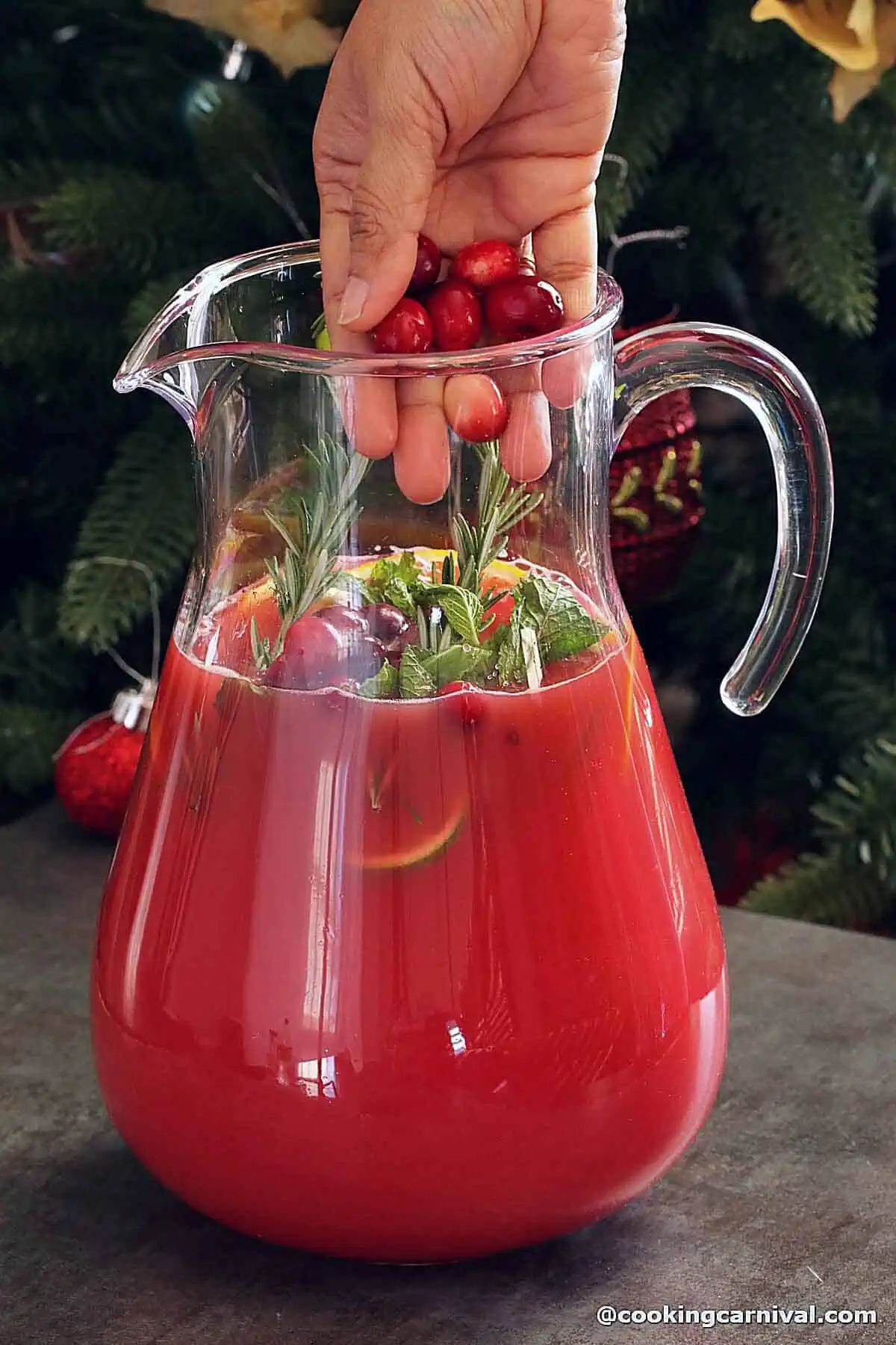 adding whole fresh cranberries in a Christmas punch jug.