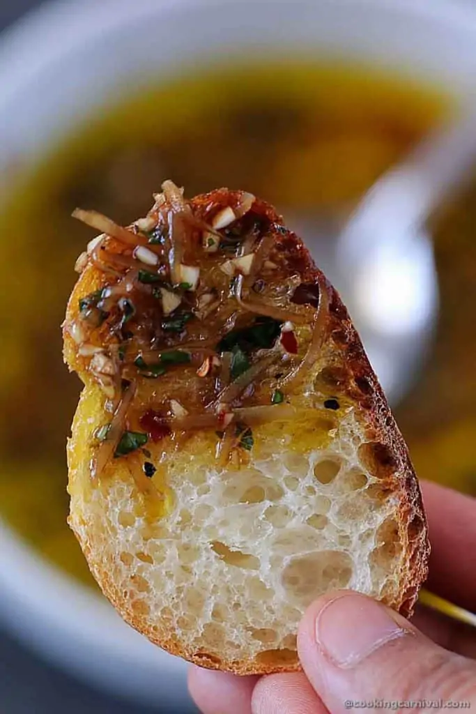 Close up shot of bread dipped on olive oil and herbs