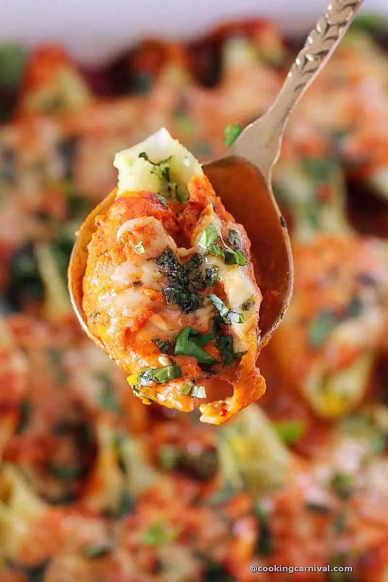 taking Paneer Vegetable stuffed shells from the pan in the spoon