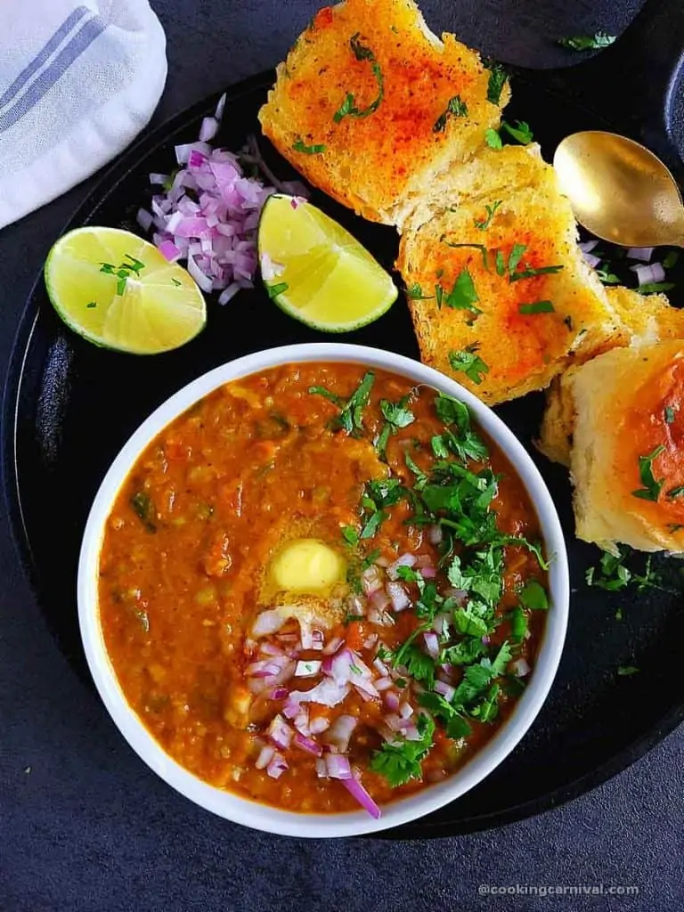 Pav bhaji in white bowl, toasted pav bread on the side