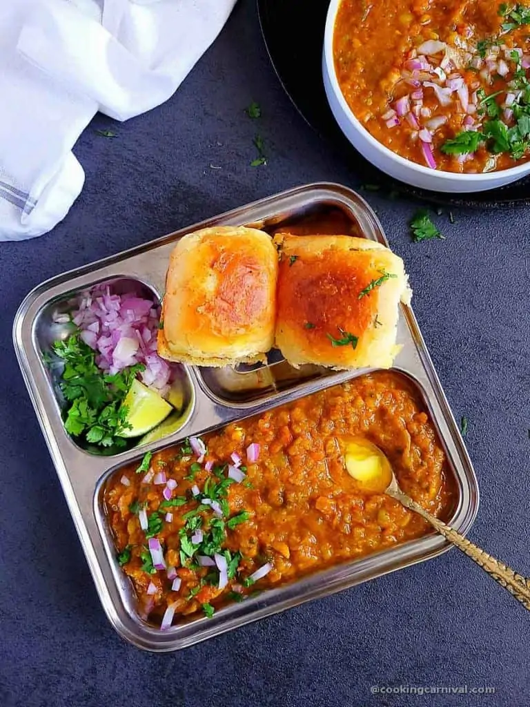 pav bhaji, pav, onion, lemon and cilanro in a plate