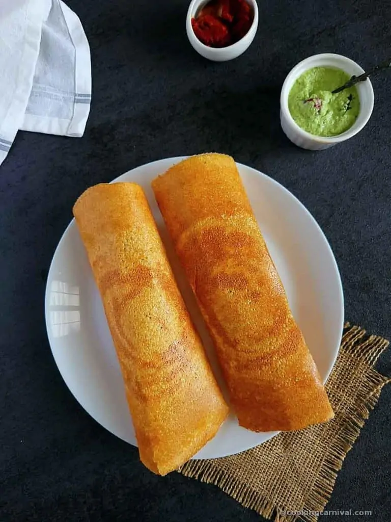 2 quinoa dosa in a white plate, coconut and garlic chutney on a side