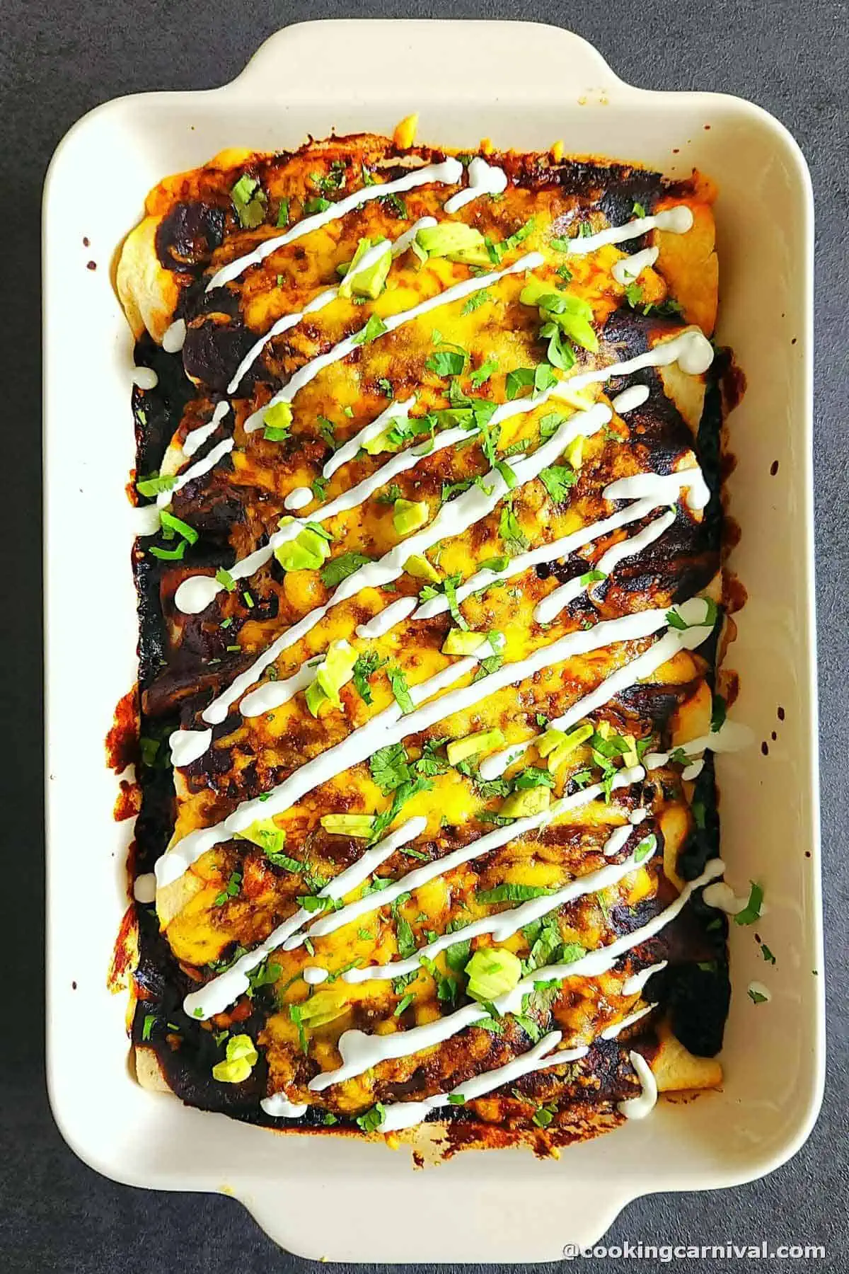 Baked vegetarian enchilada garnished with sour cream, cilantro and avocado.