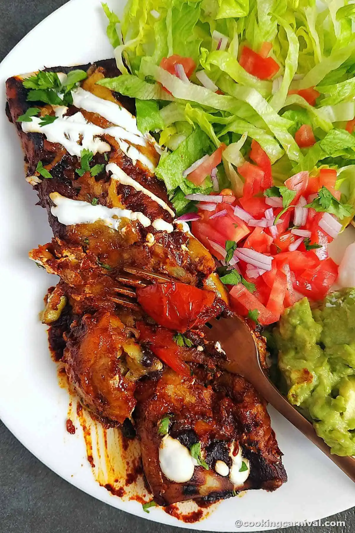 taking a bite of vegetable enchilada from a plate.