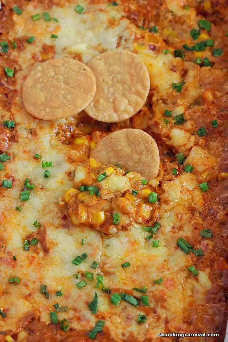 Hot corn dip served with chips in a baking dish