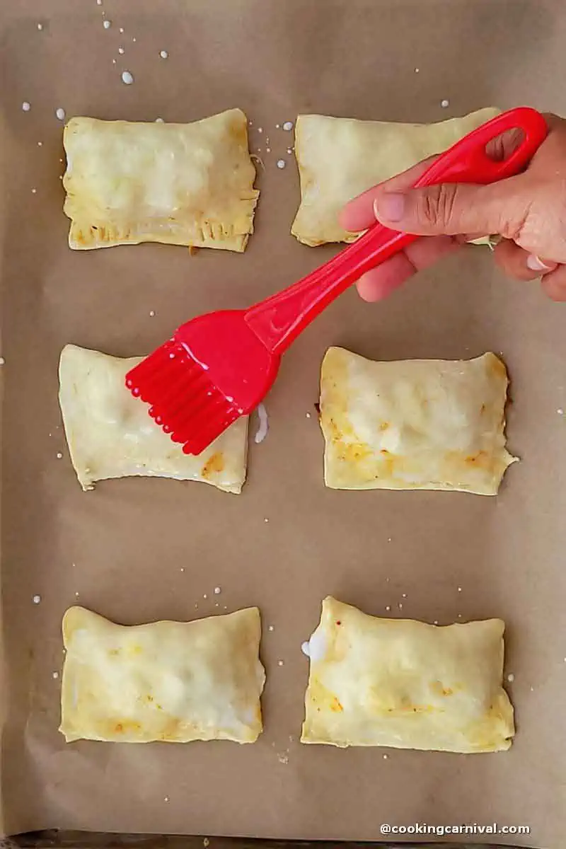 Brushing the top of the puff with milk.