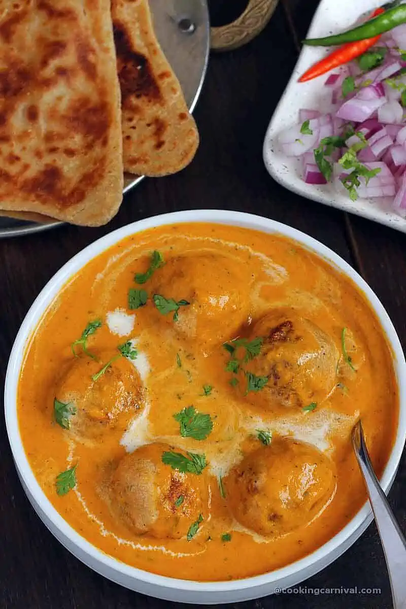 Shahi paneer kofta served with paratha and onion.