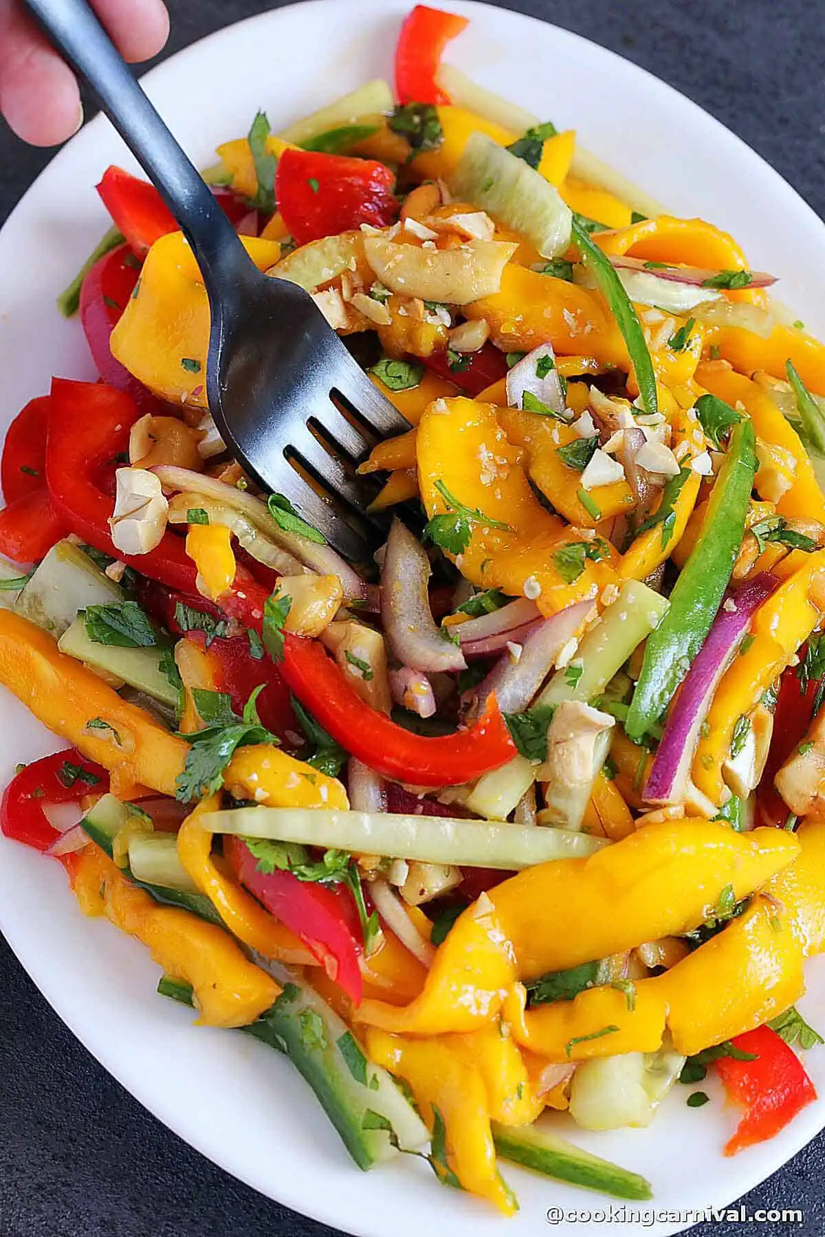 taking a bite of mango salad with a fork.