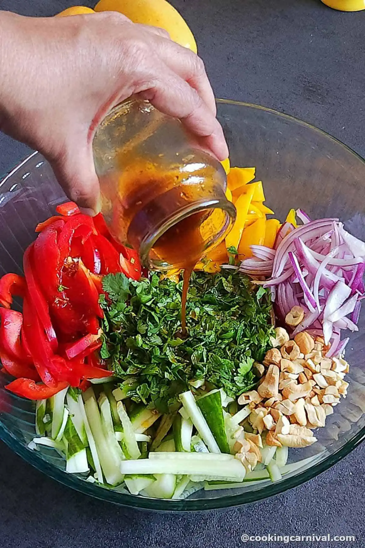 Pouring chili oil dressing over mango salad.