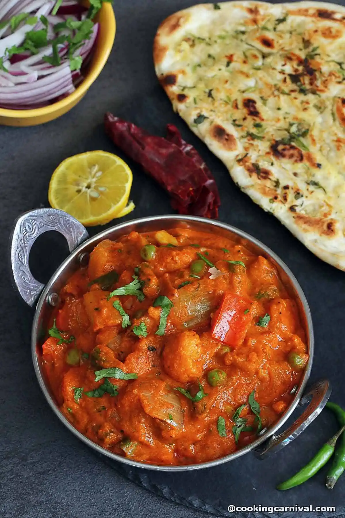 Veg Kolhapuri in a bowl, garlic naan and onion on the side