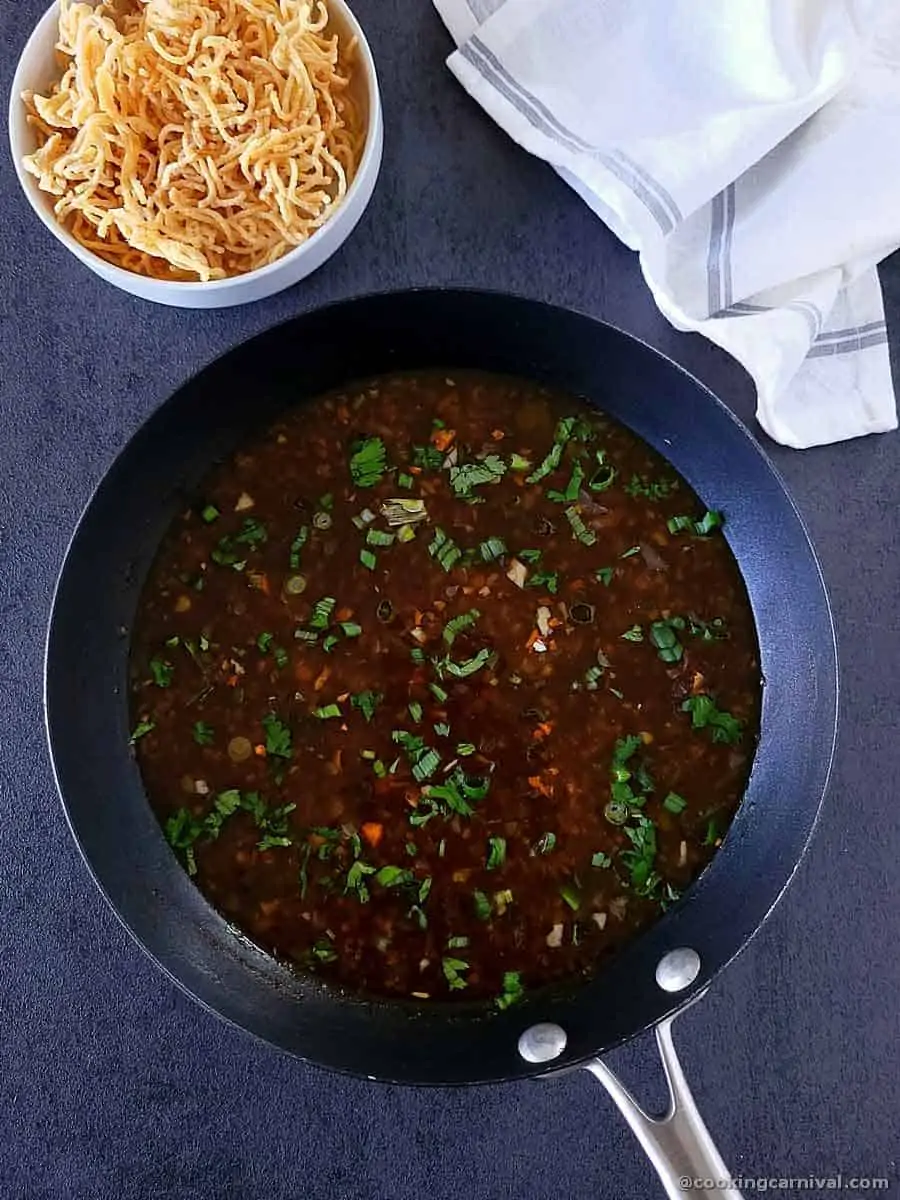 veg manchow soup in wok, fried noodles on side