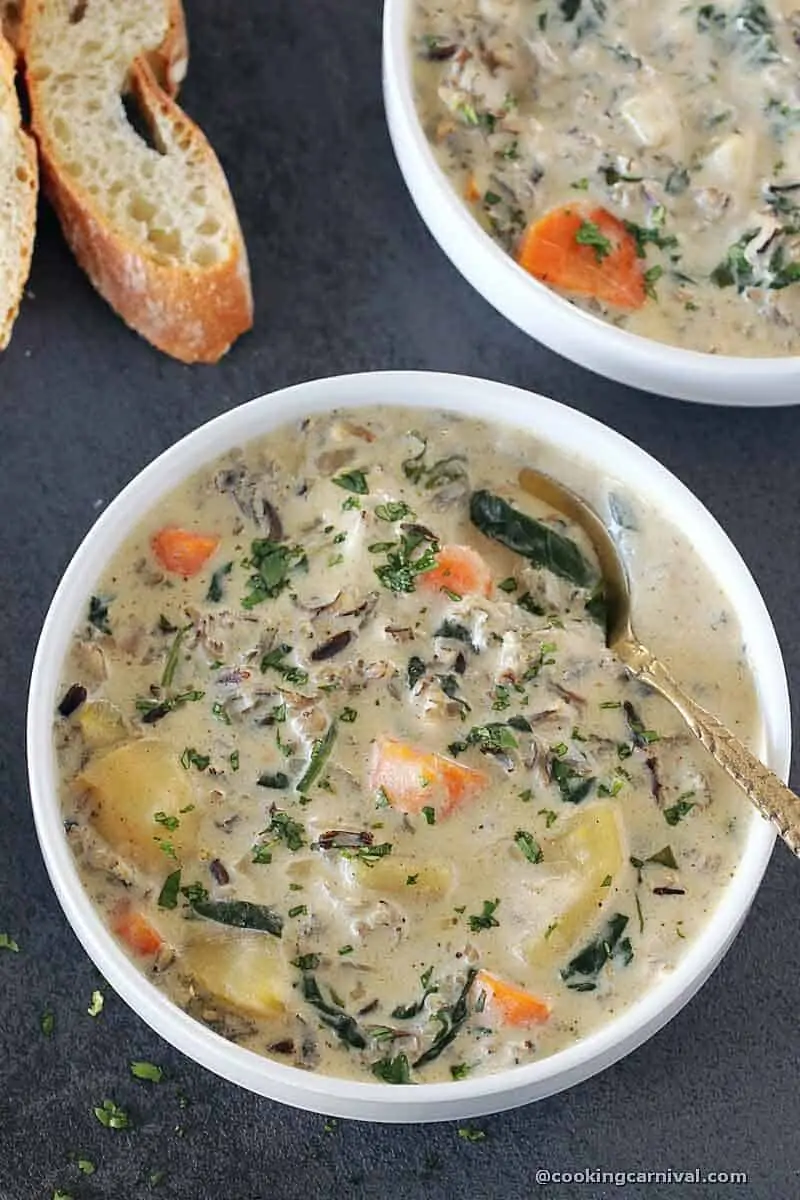 Vegetable Wild Rice Soup in a white bowl, crusty bread on side